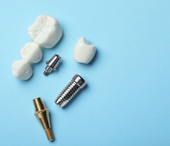 A dental bridge near an implant parts against a blue background