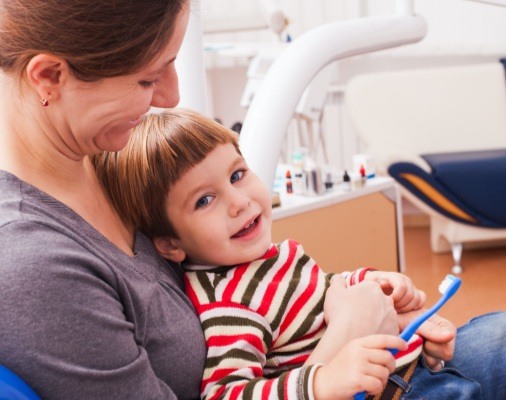 Mother holding child in lap for first dental visit