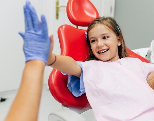 Little girl giving dentist a high-five while learning about preventive dental care