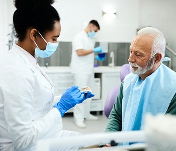 A dentist talking to a senior about dentures