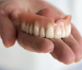 Hand holding a full denture