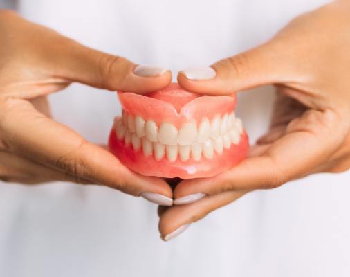 Hand holding set of full dentures