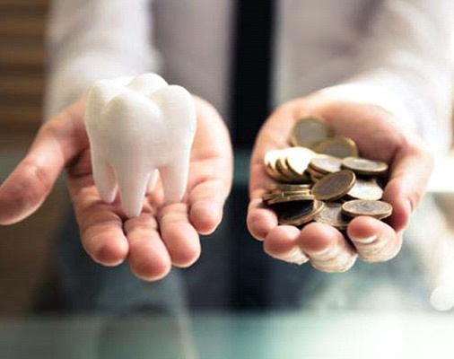 fake tooth in one hand and coins in the other