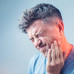 man holding the side of his face in pain