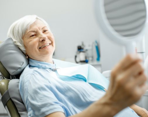 Woman looking at smile after tooth extraction and site preservation