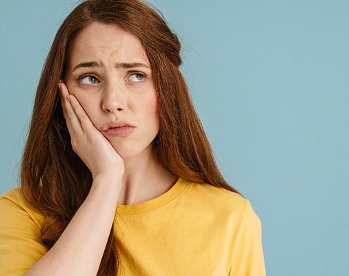 woman holding jaw while in pain 