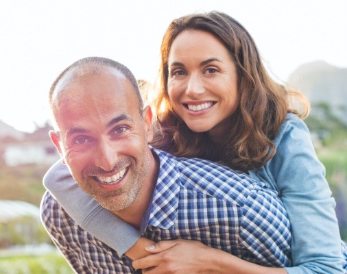 Man and woman smiling after dental implant tooth replacement