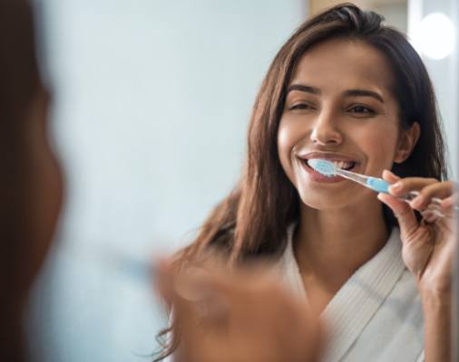 Woman brushing teeth after dental implant tooth replacement