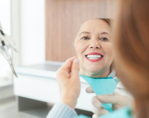 Woman looking at smile in mirror after makeover