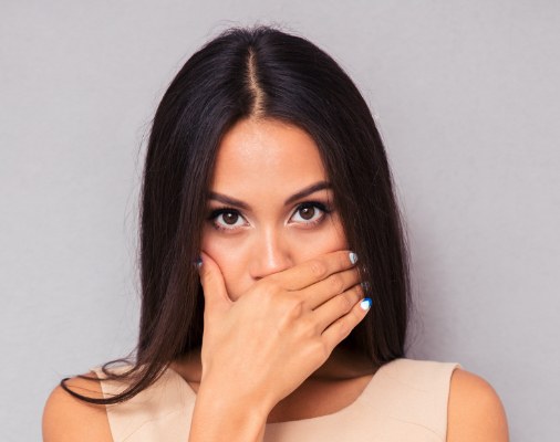 Woman in need of halitosis treatment covering her mouth