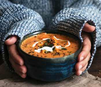 Hands holding a bowl of soup