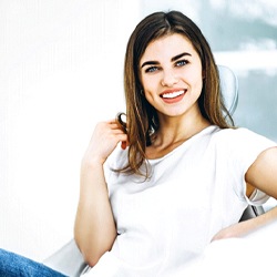 Woman in white shirt smiling in the dental chair