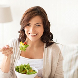 Woman smiling while eating a green salad