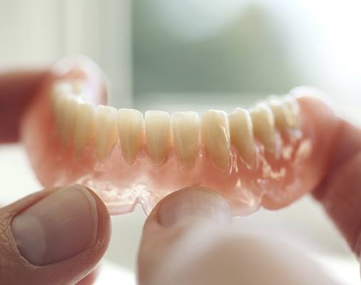 Hand holding a full denture