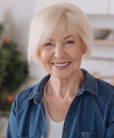 Woman with full smile after dental implant tooth replacement