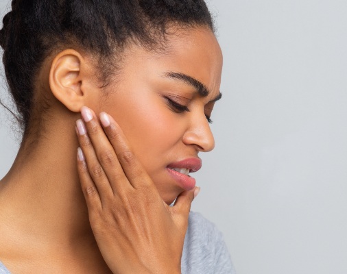 Woman in need of T M J therapy holding jaw