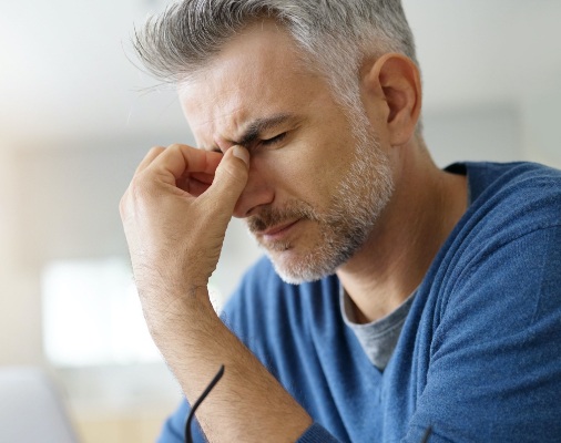 Man in need of T M J therapy holding head in pain