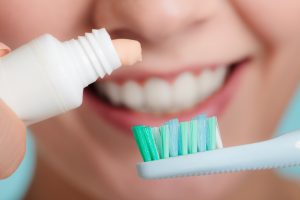 woman squeezing whitening toothpaste onto toothbrush