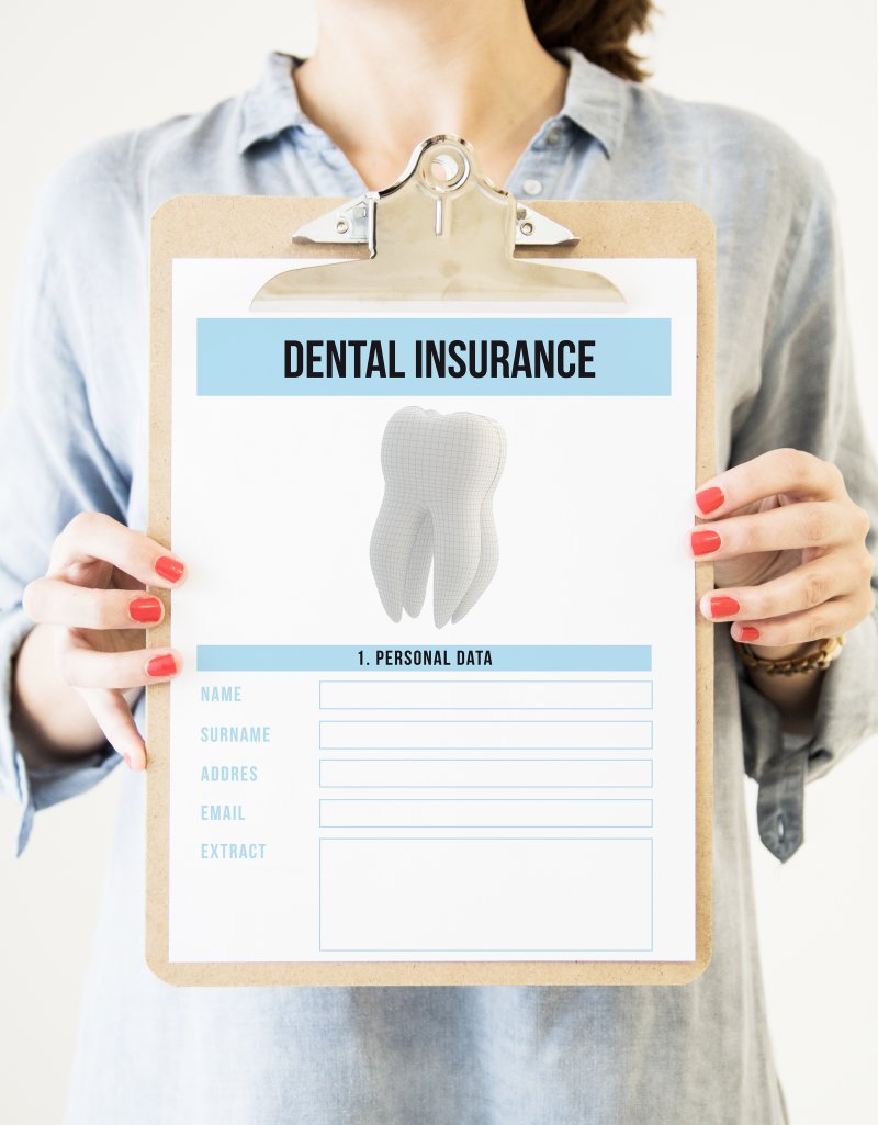 Holding up a clipboard with a dental insurance form