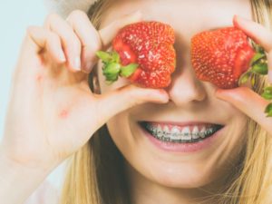 Smiling teen with braces in Mt. Holly holding strawberries