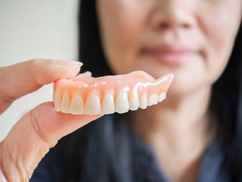 A hand holding an upper denture