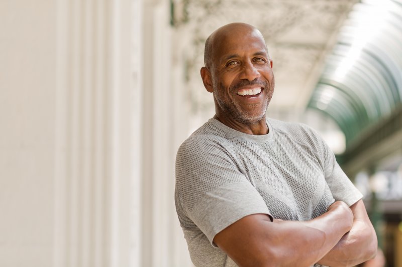 Mature man with dental implants smiling in gray shirt