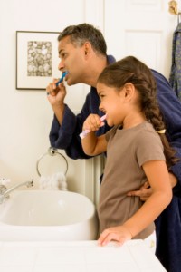 father and daughter brushing teeth to maintain oral health